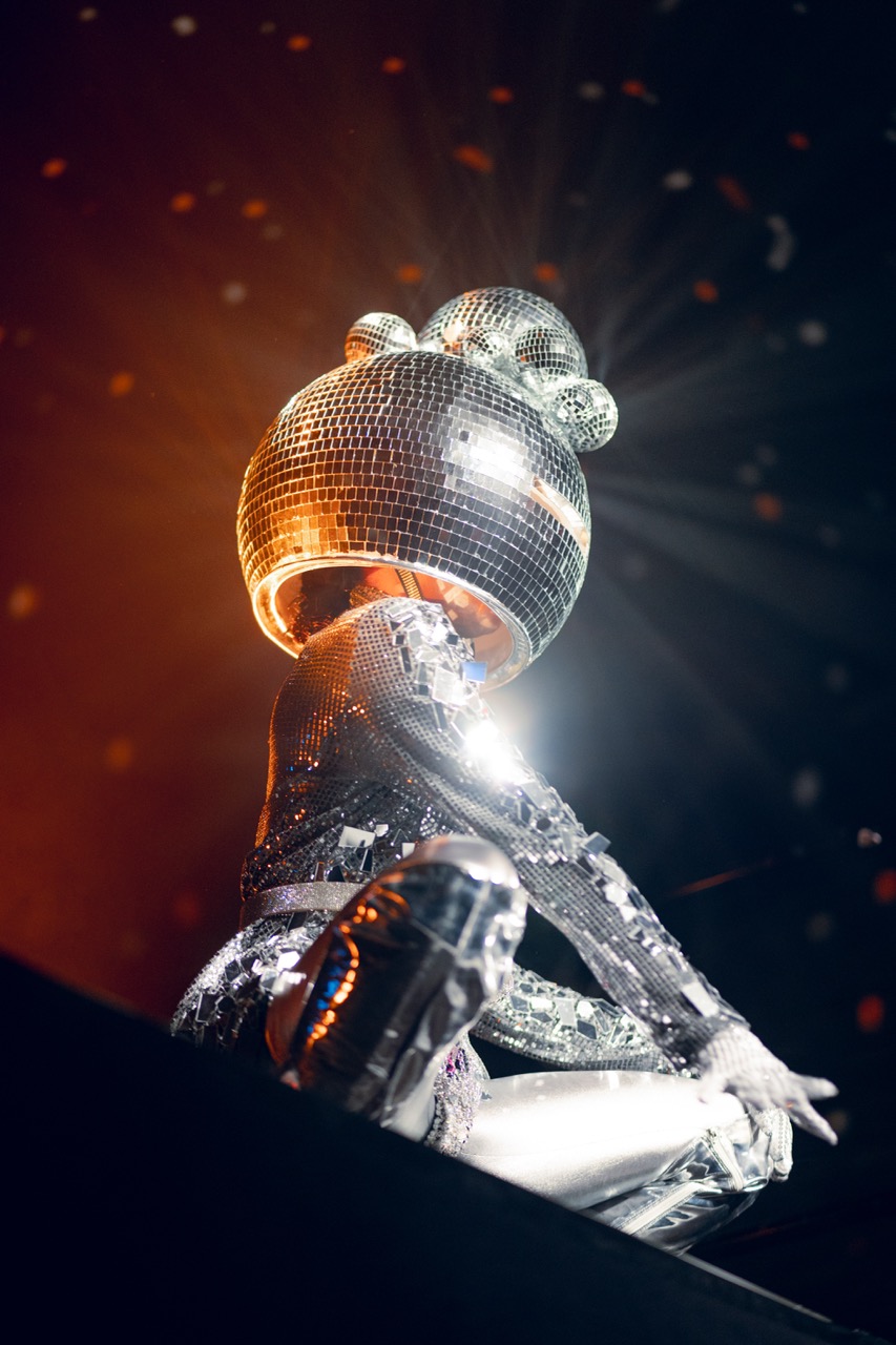 A performer in mirrored costume under stage light