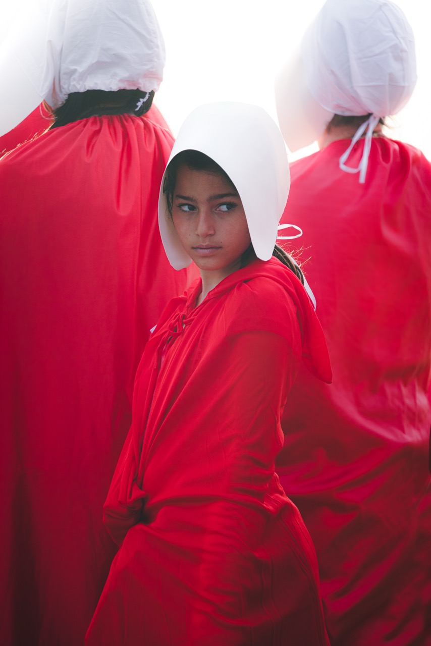 A young woman in a red robe looking back toward the camera